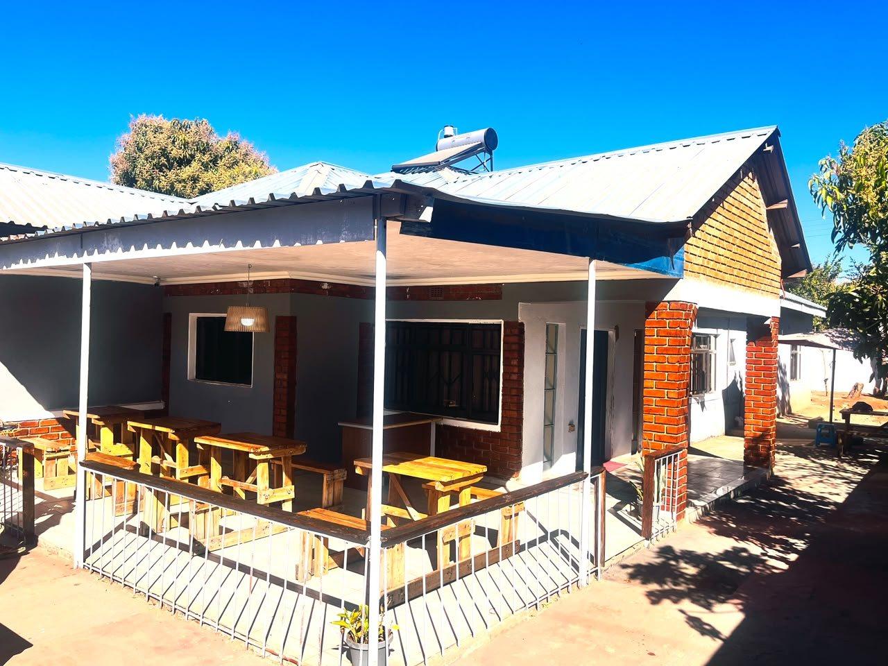 Covered veranda with wooden dining tables and benches at Fallsview Guest House