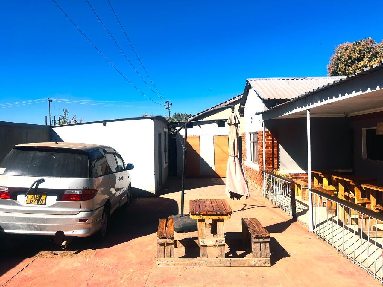 Paved courtyard with a picnic table and a parked car inside the grounds of Fallsview Guest House