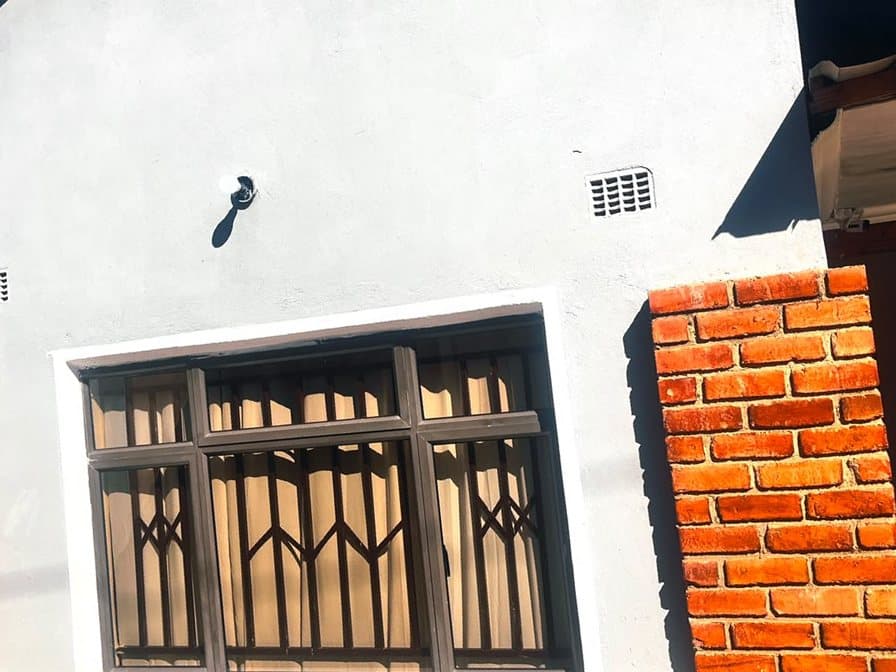 Grey rendered guest wing with a large window and face-brick pillars at Fallsview Guest House