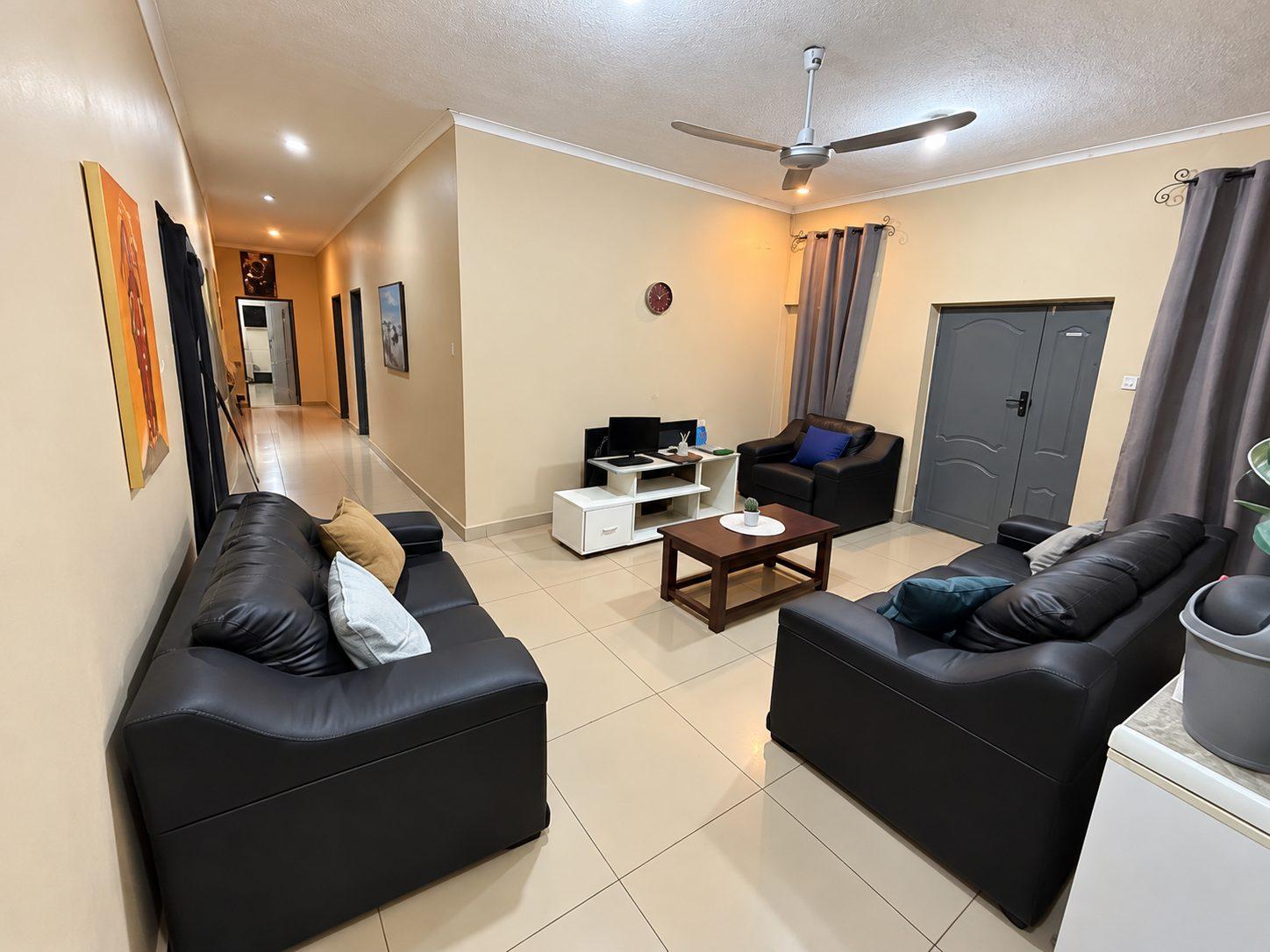 Lounge with leather sofas and a ceiling fan, opening onto a tiled hallway at Fallsview Guest House
